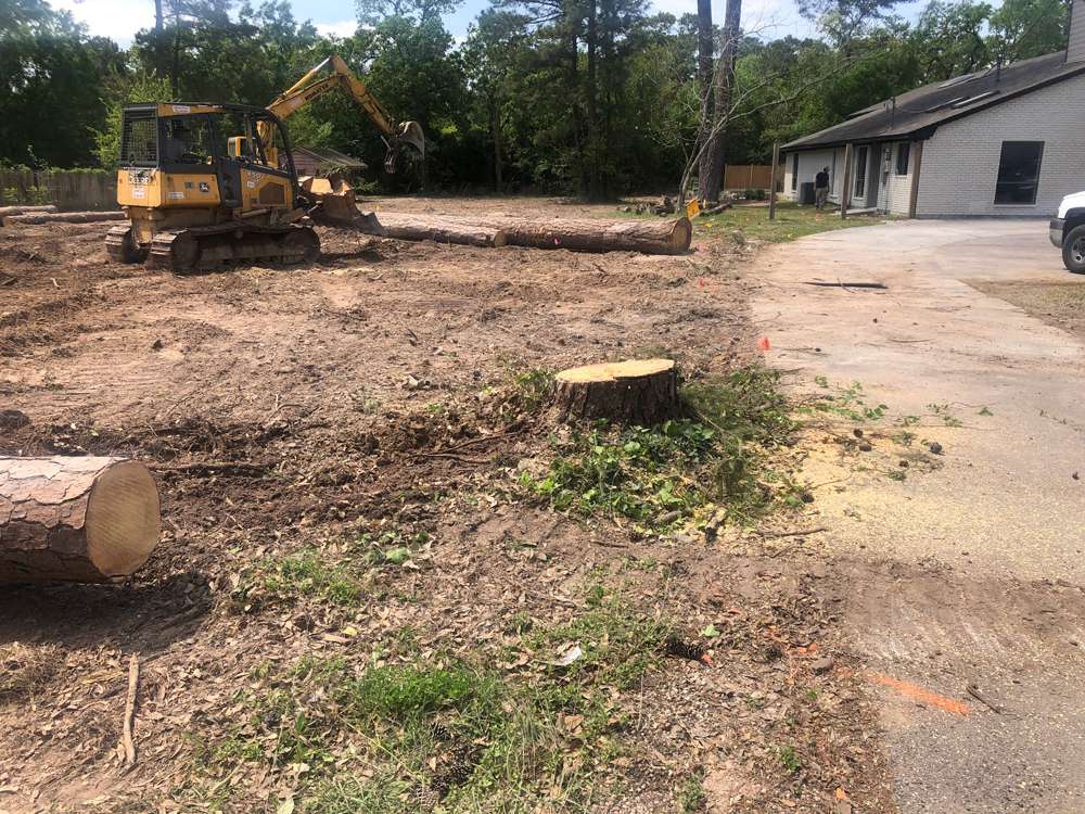 Residential land clearing project near Houston showing an excavator removing brush